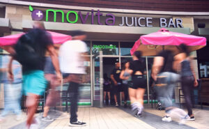 People walking in front of a Movita Juice Bar location